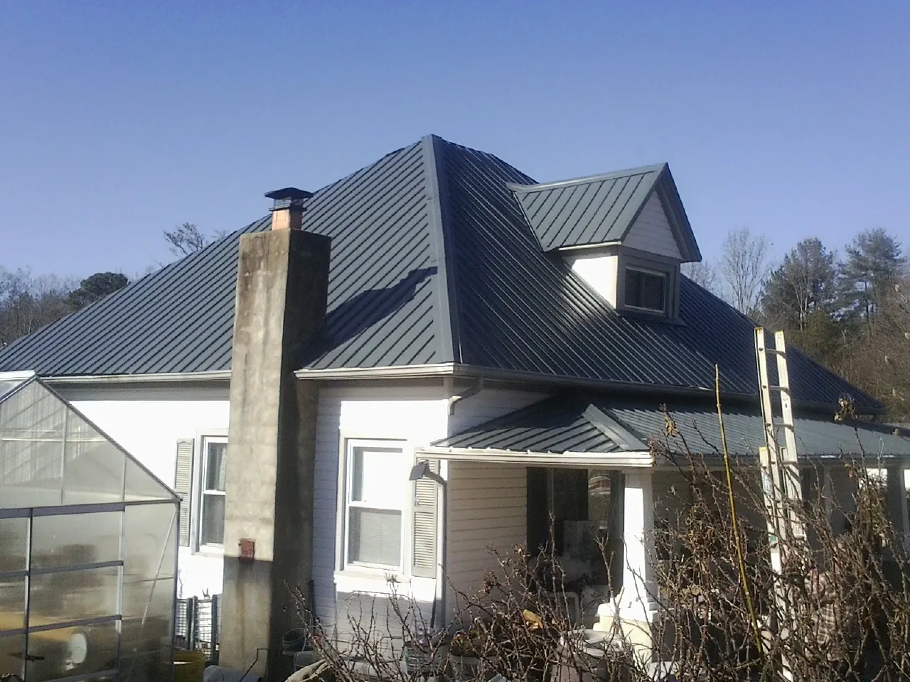 Dark blue standing seam metal roof on a white farmhouse with dormer — Slate & Tile Roof Repair by Roofing Brothers in Palmdale