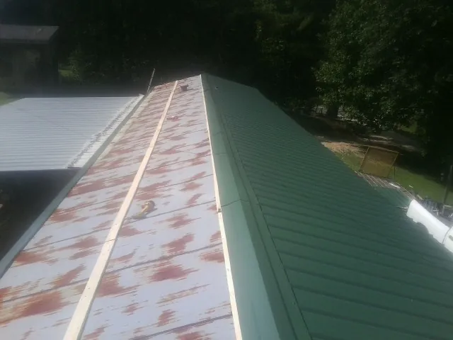 Old rusted panels beside newly installed green metal roofing — Wind Damage Roof Repair by Roofing Brothers in Palmdale