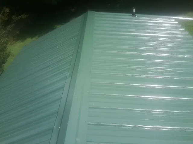 New green metal panels meeting at the ridge of a roof — Flat Roof Repair work by our crew in Palmdale
