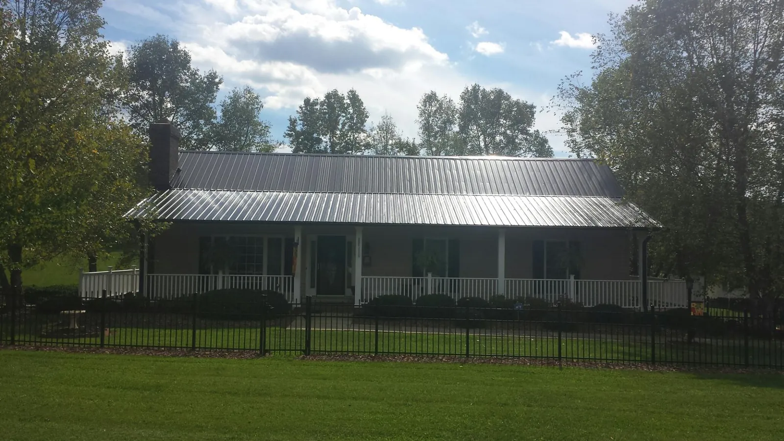 Gray metal roof on a brick ranch with a full width front porch — Gutter Guard Installation work by our crew in Palmdale