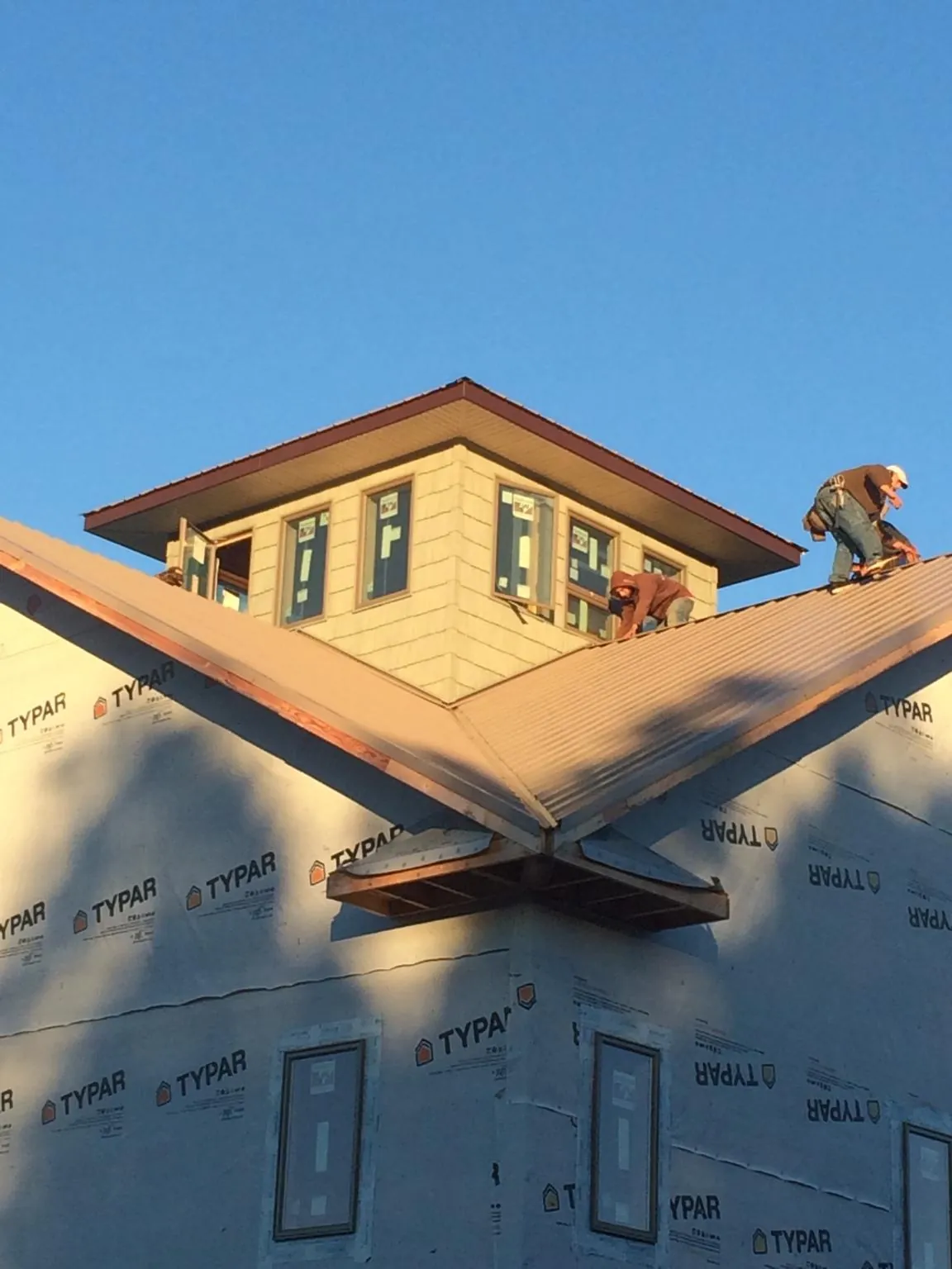 Roofers working around a rooftop cupola on a new metal roof at sunset — Roof Waterproofing in Palmdale by Roofing Brothers